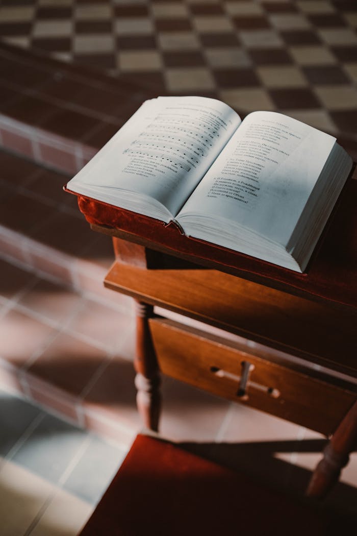 Man studying and taking notes with a Bible on a desk indoors.